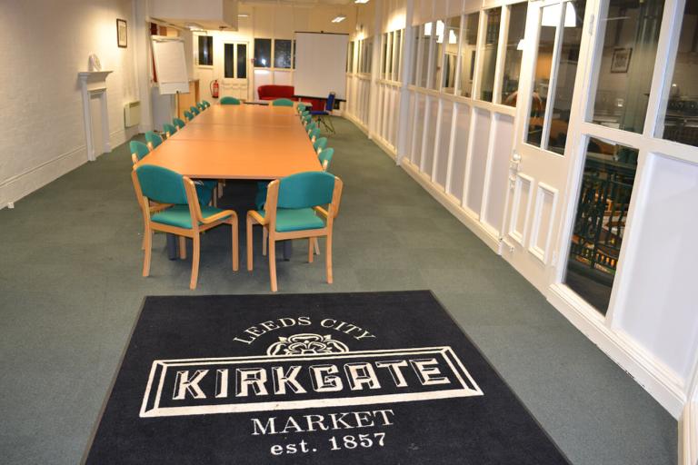 a room containing a long table, several chairs and a large floor mat